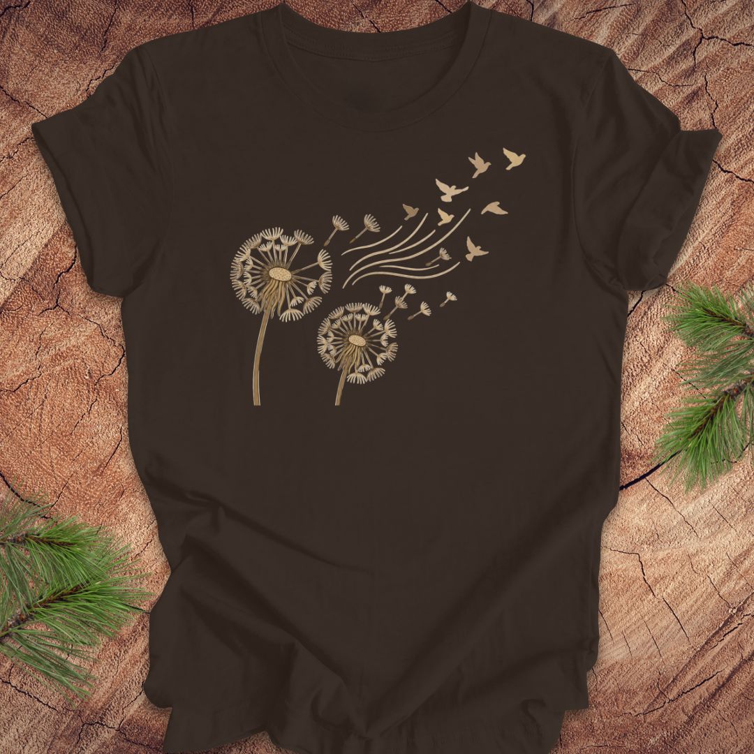Brown t-shirt with dandelion and bird design on a wooden surface