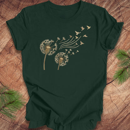 Green t-shirt with dandelion and bird design on a wooden surface