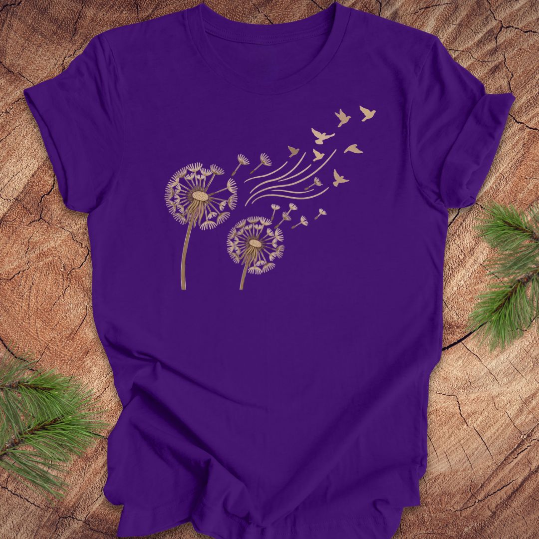 Purple t-shirt with dandelion and bird design on a wooden surface