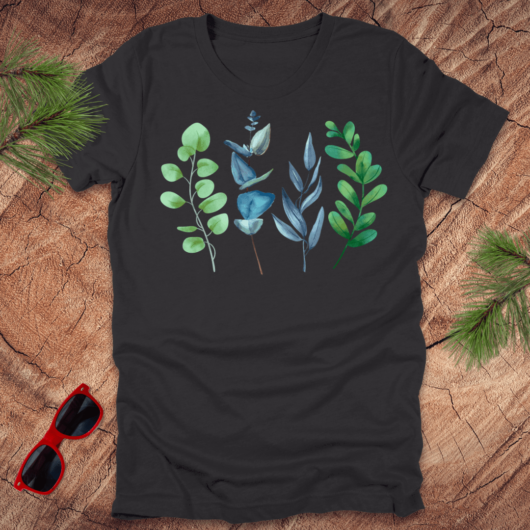 Black t-shirt with leaf designs on a wooden surface with sunglasses and greenery.