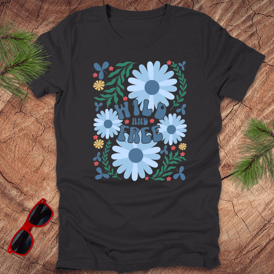 Black t-shirt with floral design and text on a wooden surface with sunglasses and greenery.