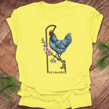Yellow t-shirt with a rooster and floral design on a wooden surface