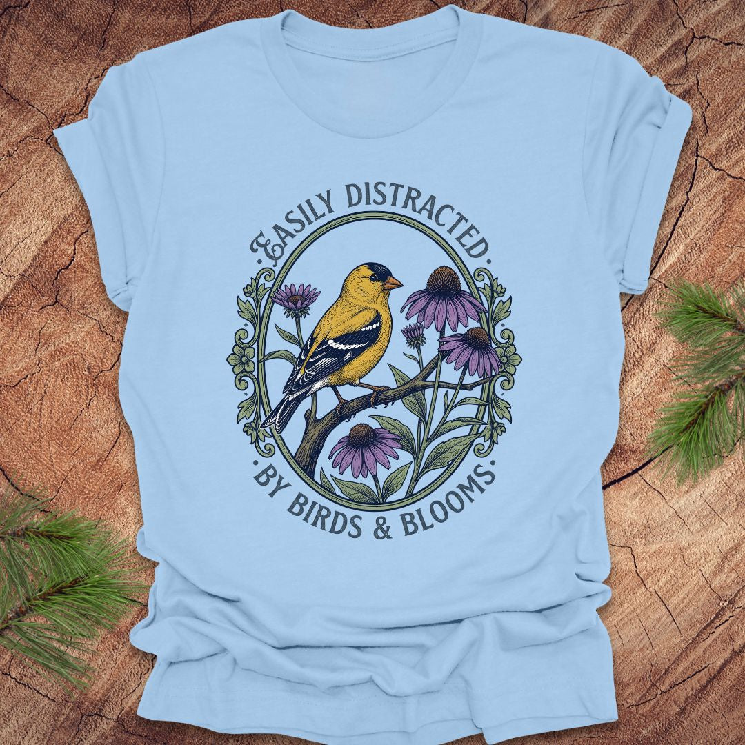 Light blue t-shirt with a bird and floral design on a wooden surface