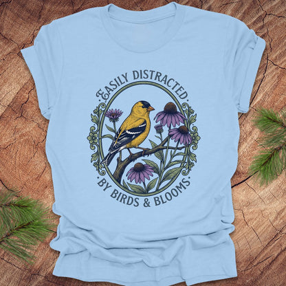 Light blue t-shirt with a bird and floral design on a wooden surface