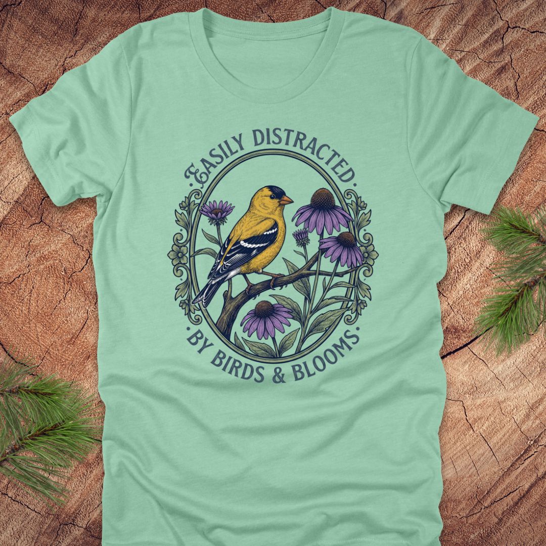 Light green t-shirt with a bird and floral design on a wooden surface