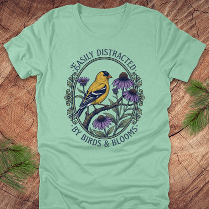 Light green t-shirt with a bird and floral design on a wooden surface