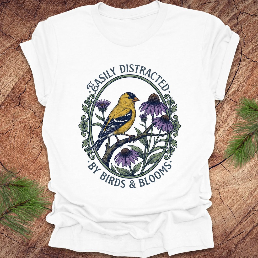 White t-shirt with a bird and floral design on a wooden surface