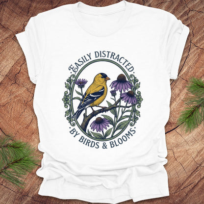 White t-shirt with a bird and floral design on a wooden surface
