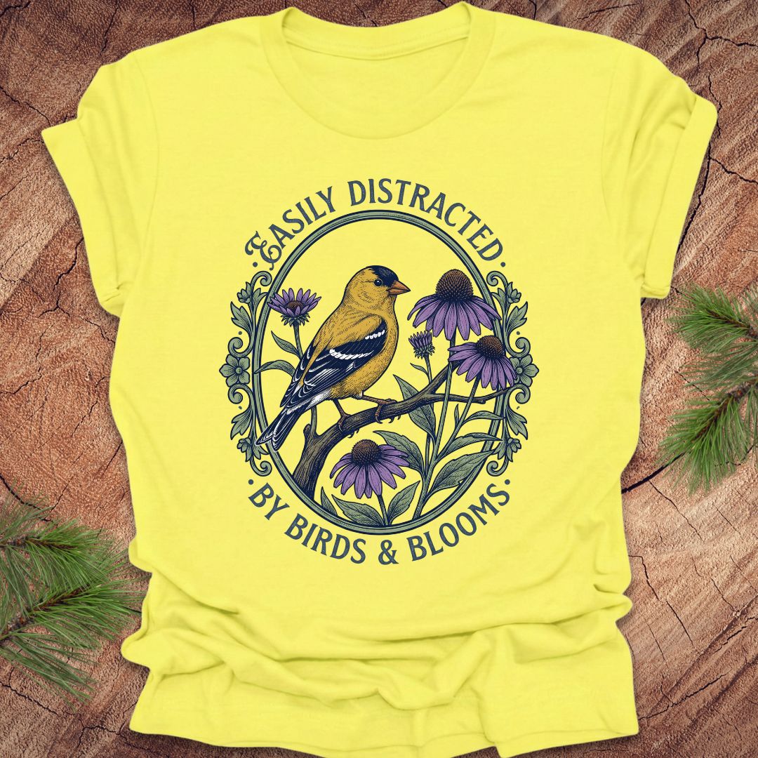 Yellow t-shirt with a bird and floral design on a wooden surface