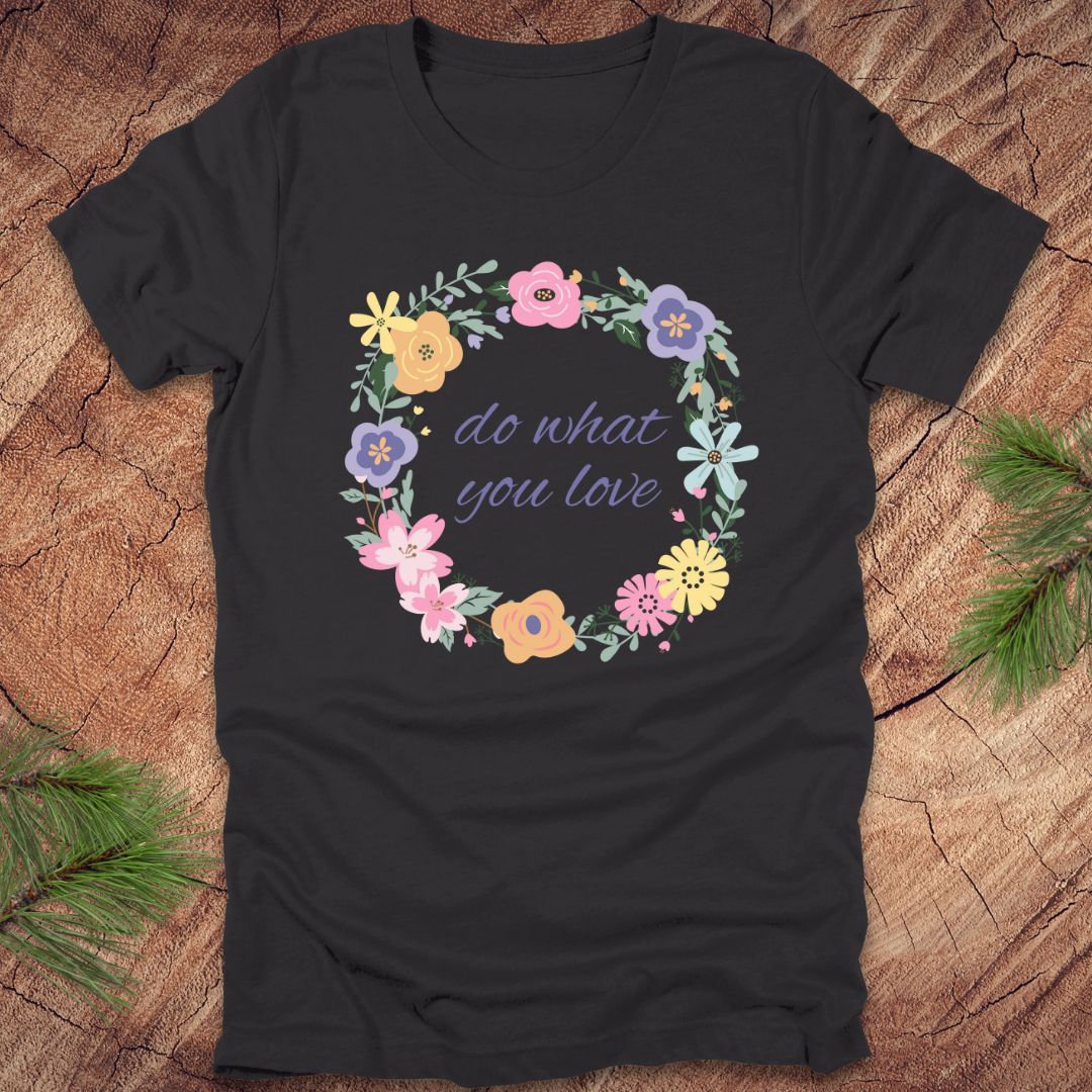 A Dark grey t-shirt with a floral wreath design and text, 'Do what you love' on a wood background.