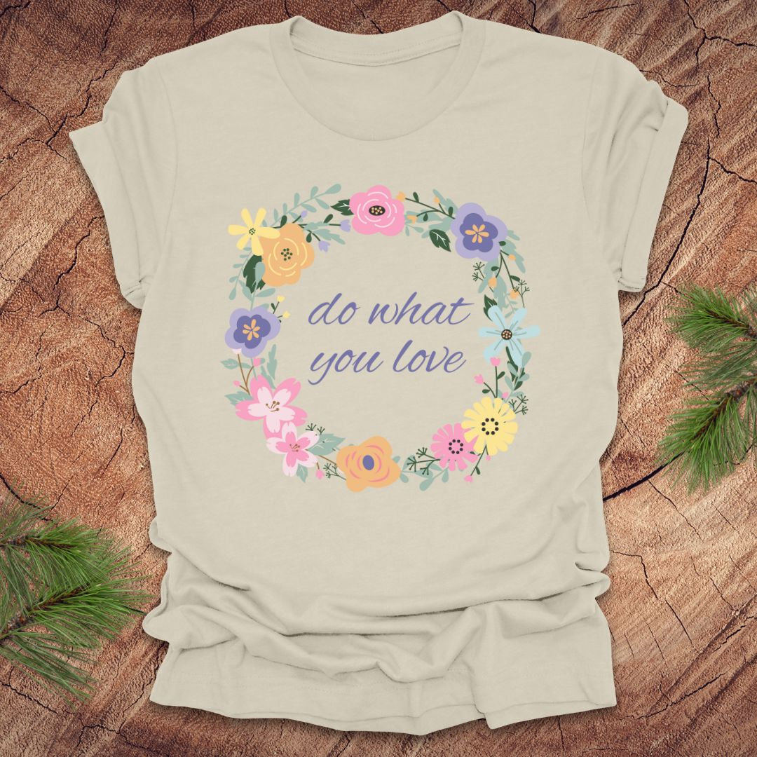 A Beige t-shirt with a floral wreath design and text, 'Do what you love' on a wood background.