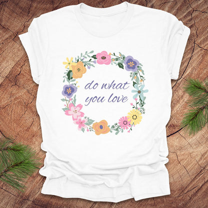 A White t-shirt with a floral wreath design and text, 'Do what you love' on a wood background.