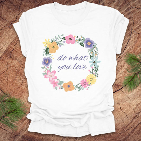 A White t-shirt with a floral wreath design and text, 'Do what you love' on a wood background.