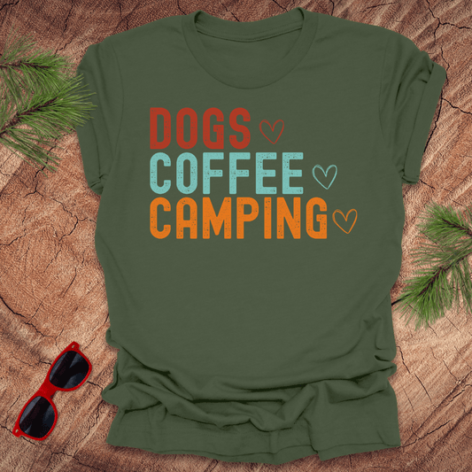 Green t-shirt with text, Dogs, Coffee, Camping on a wood background with sunglasses. 