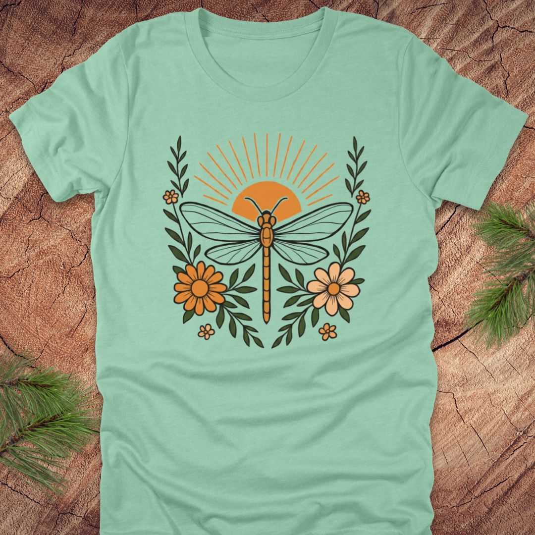 Mint green t-shirt with a dragonfly and floral design on a wooden surface