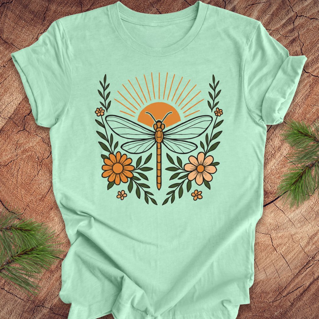 Mint green t-shirt with a dragonfly, sunrise and flowers on a wood background.