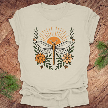 Beige t-shirt with a dragonfly and floral design on a wooden surface