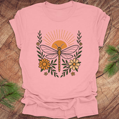 Pink t-shirt with a dragonfly and floral design on a wooden surface