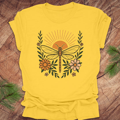 Yellow t-shirt with a dragonfly and floral design on a wooden surface