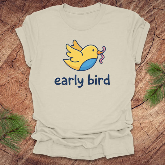 Beige t-shirt with a cartoon bird and 'early bird' text on a wooden surface