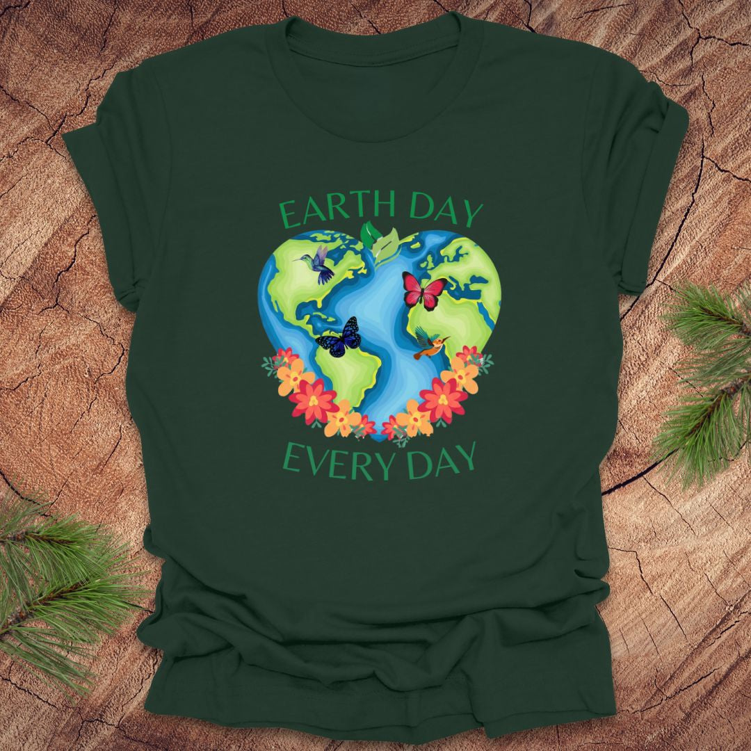 Green t-shirt with Earth Day design featuring the Earth, flowers, and butterflies on a wooden surface.