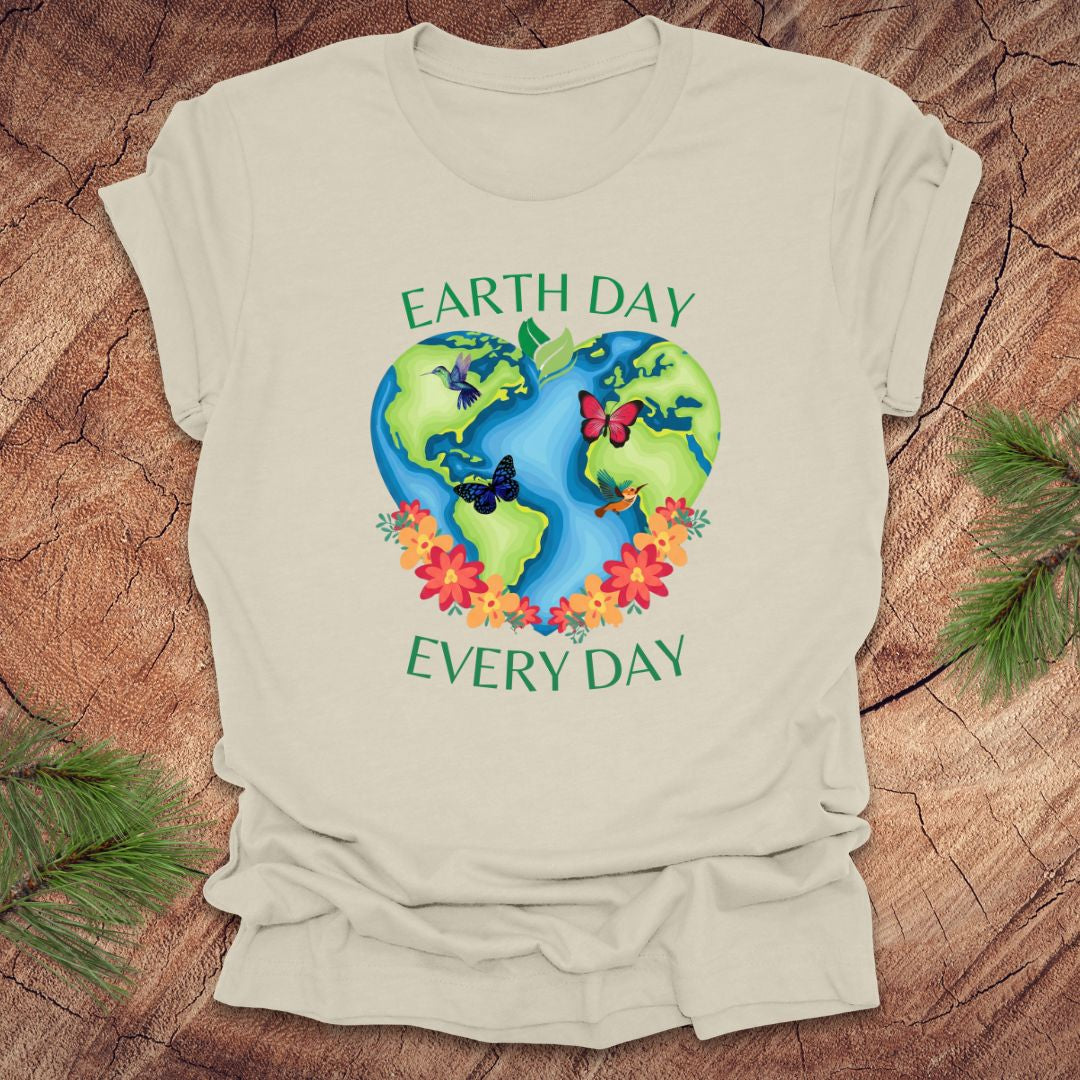 Beige t-shirt with Earth Day design featuring the Earth, flowers, and butterflies on a wooden surface.