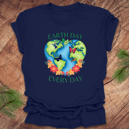 Navy t-shirt with Earth Day design featuring the Earth, flowers, and butterflies on a wooden surface.