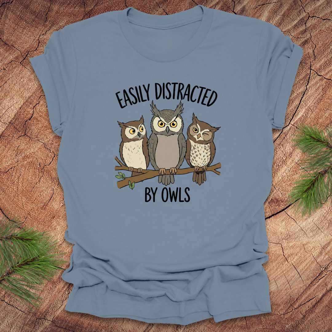 Steel blue t-shirt with owl design and text 'Easily Distracted by Owls' on a wooden background