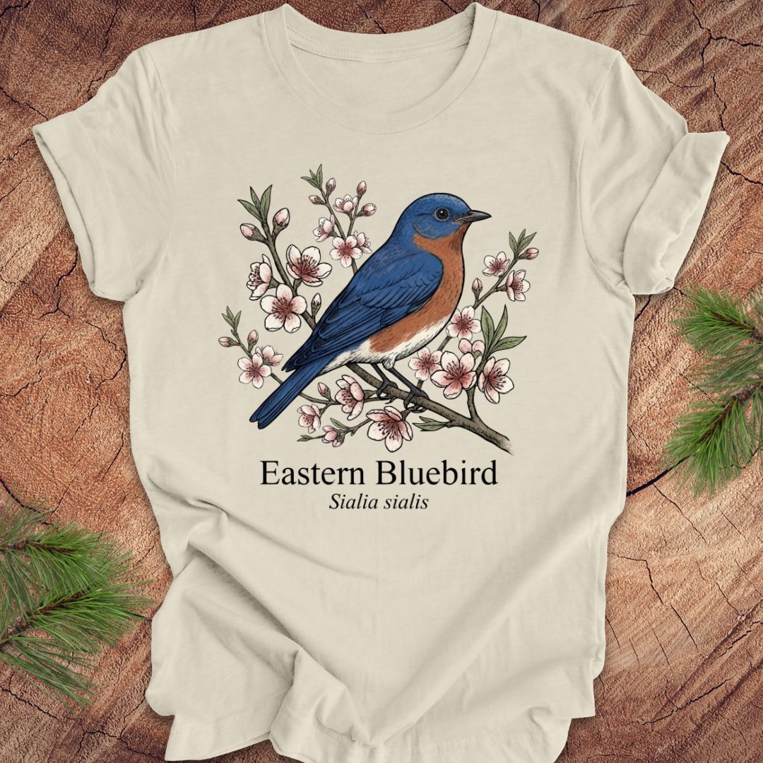 Beige t-shirt with an illustration of an Eastern Bluebird on a wooden surface