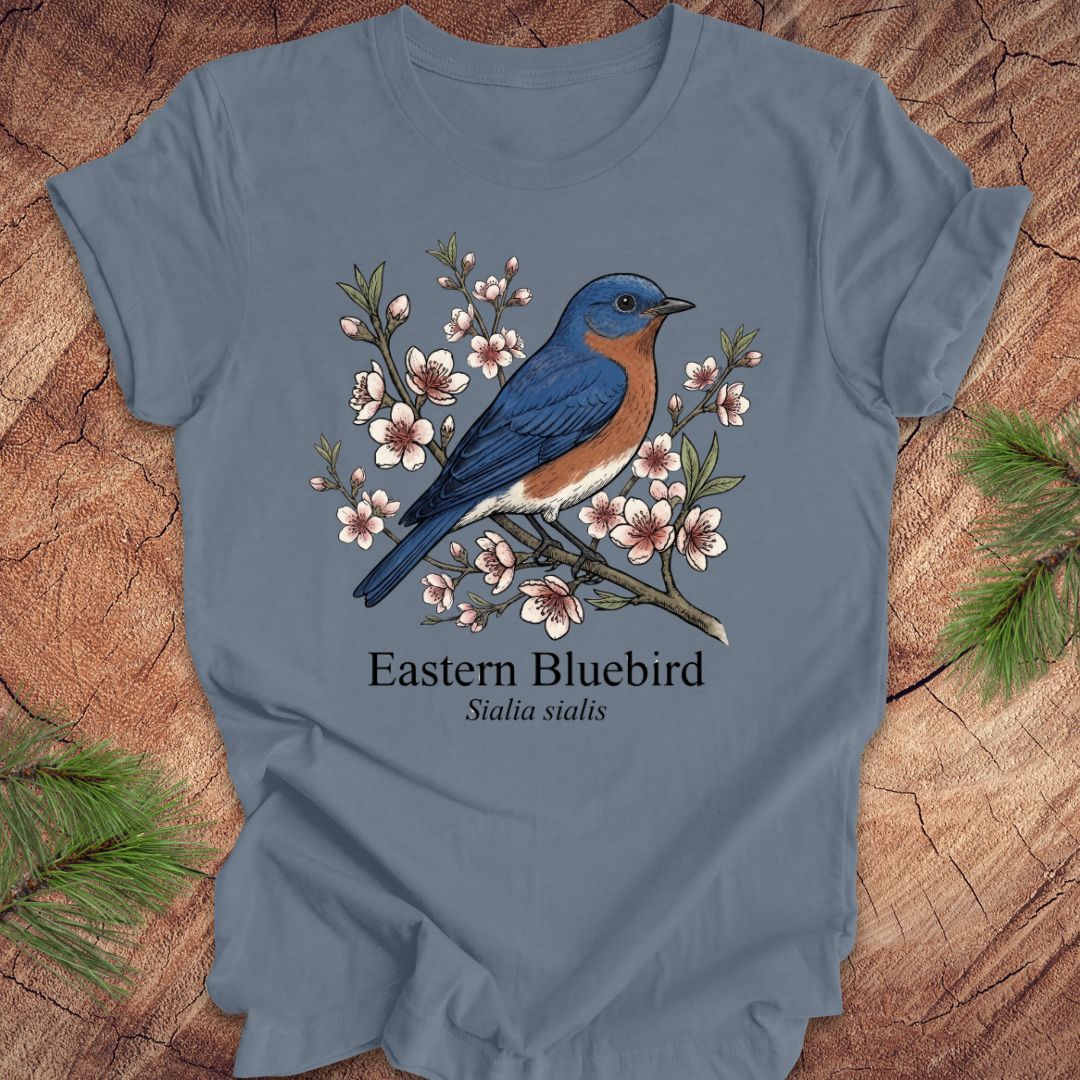 Blue t-shirt with an illustration of an Eastern Bluebird on a wooden surface