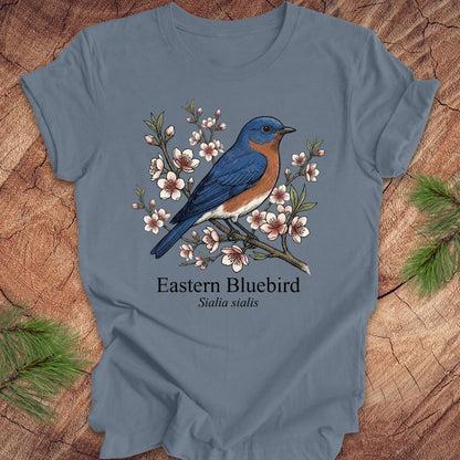 Blue t-shirt with an illustration of an Eastern Bluebird on a wooden surface