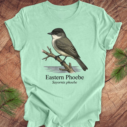 Mint green t-shirt with an illustration of an Eastern Phoebe bird on a wooden surface.