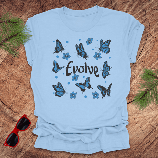 baby blue t-shirt with butterfly design and 'Evolve' text on a wooden surface with sunglasses and greenery