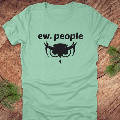 Light green t-shirt with 'ew. people' text and owl design on a wooden surface.