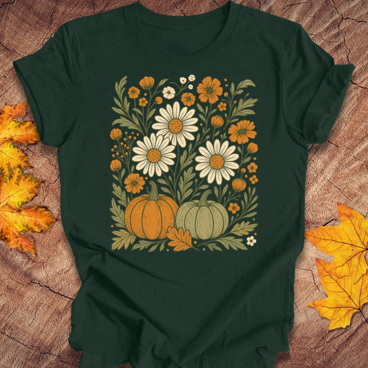 A dark forest green short-sleeve t-shirt with a vintage-style autumn floral graphic, laid flat on a rustic wood background with yellow and orange leaves.