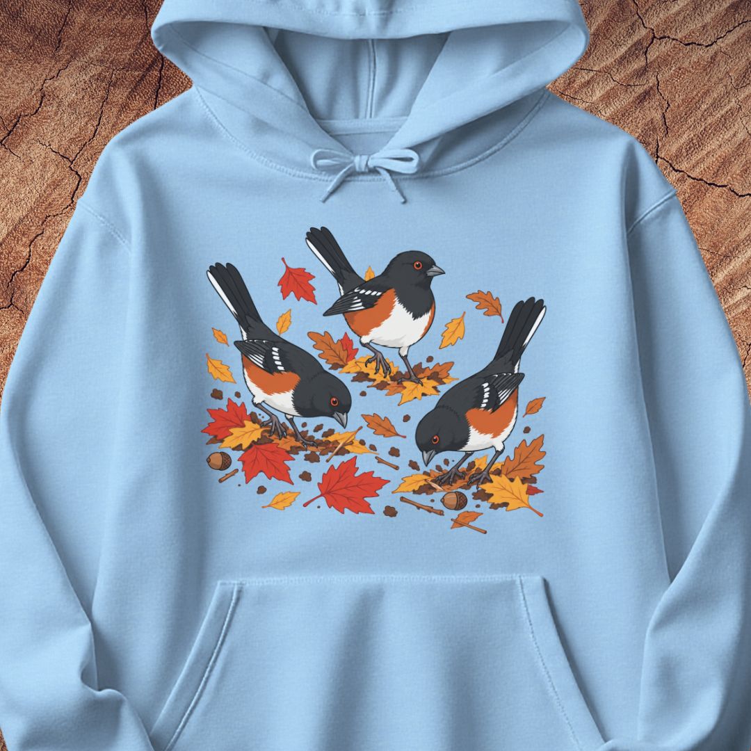 A light blue hooded sweatshirt with 3 towhee birds among fall leaves, on a wood background.