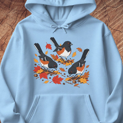 A light blue hooded sweatshirt with 3 towhee birds among fall leaves, on a wood background.