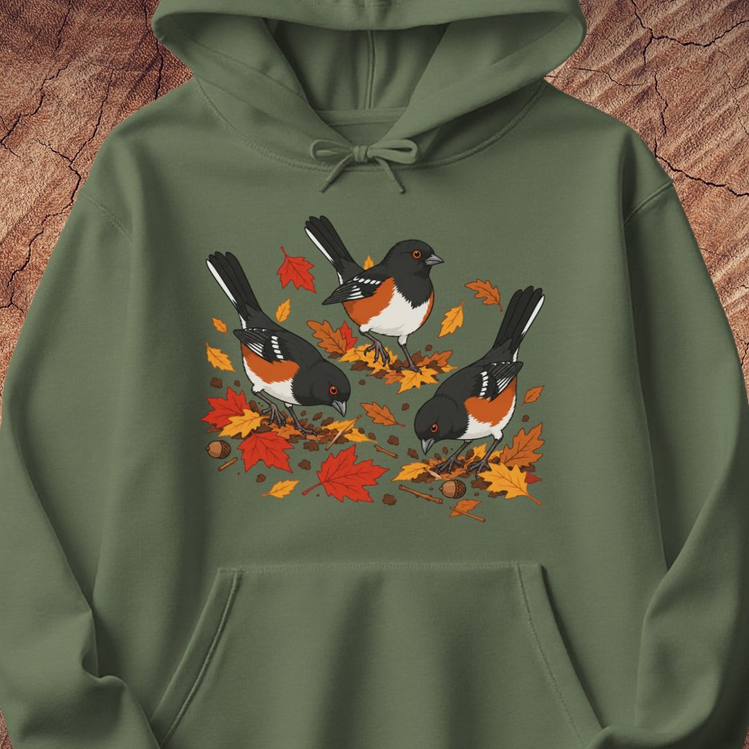 A green hooded sweatshirt with 3 towhee birds among fall leaves, on a wood background.