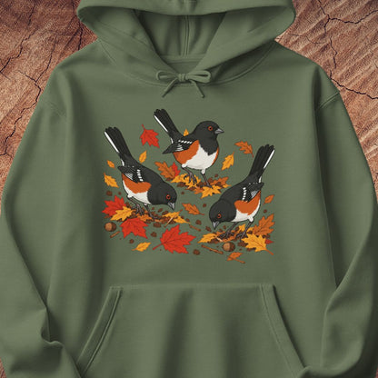 A green hooded sweatshirt with 3 towhee birds among fall leaves, on a wood background.