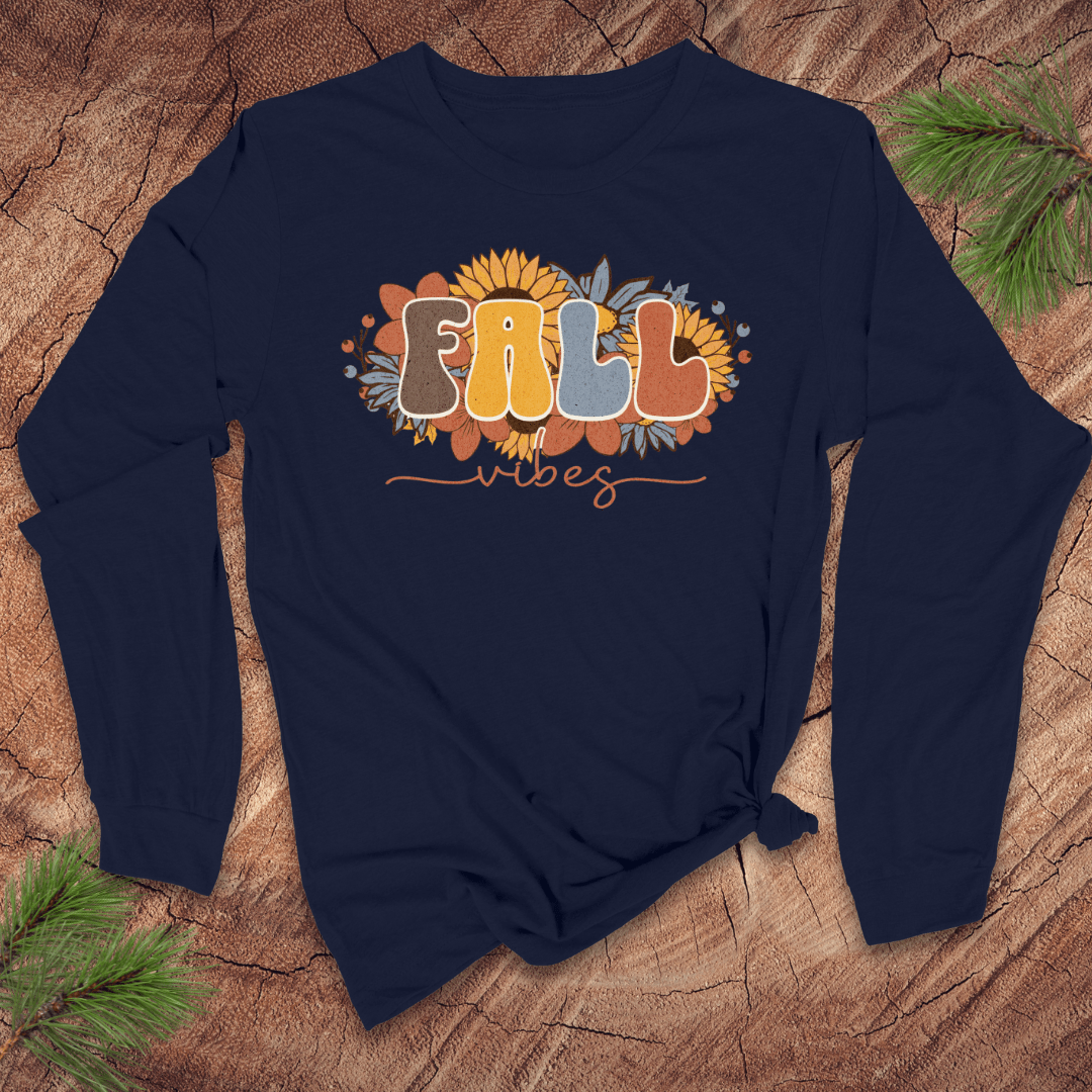 Navy blue long-sleeve shirt with 'Fall vibes' text and sunflower design on a wooden surface.