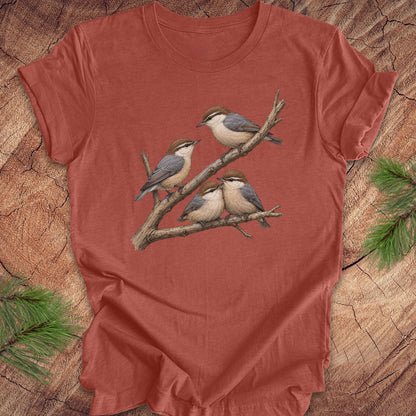 Clay colored t-shirt with nuthatch bird design on a wooden surface
