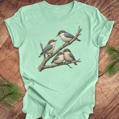 Mint green t-shirt with nuthatch bird design on a wooden surface