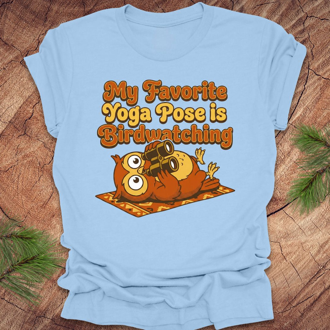 Light blue t-shirt with owl design and text 'My Favorite Yoga Pose is Birdwatching' on a wooden surface.