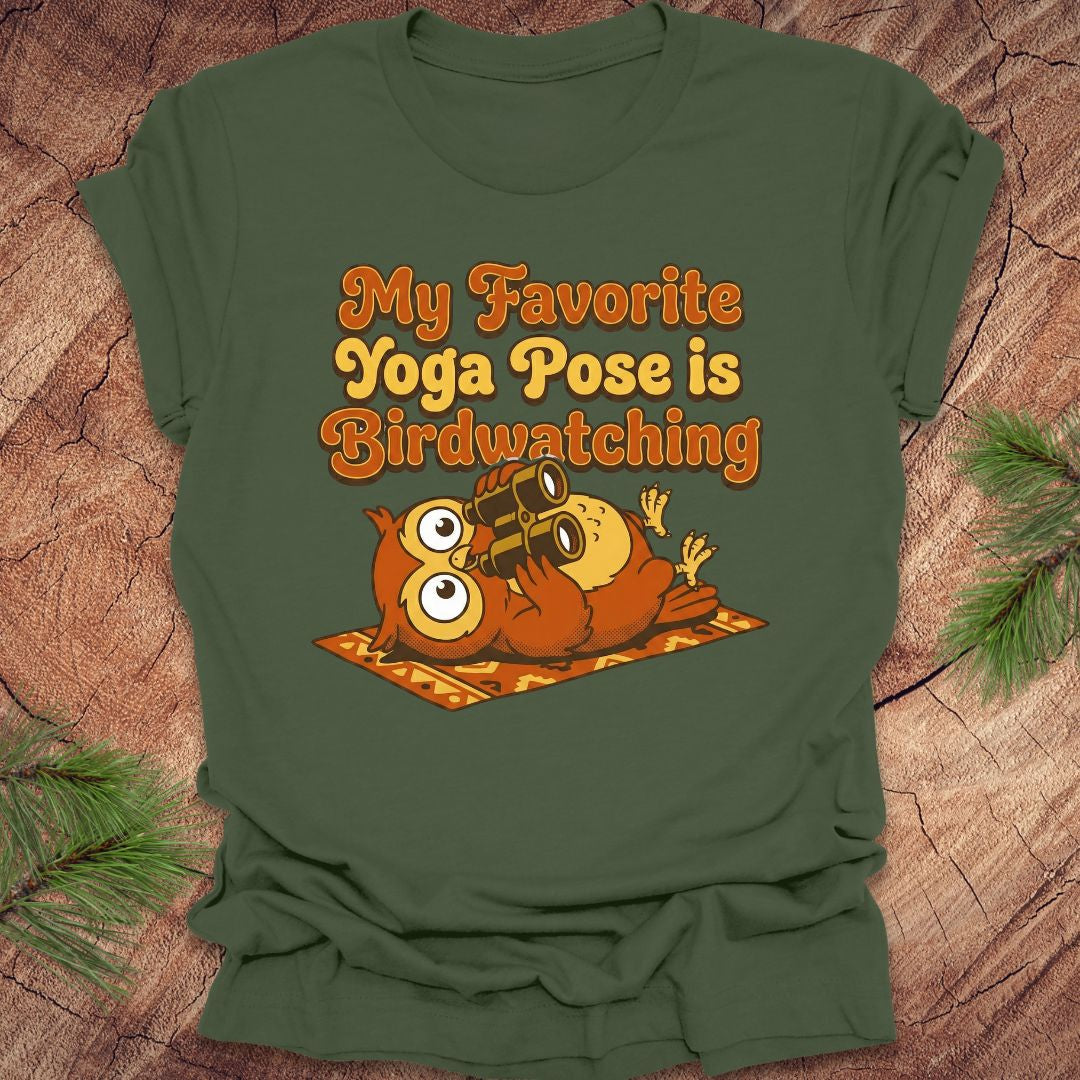 Green t-shirt with owl design and text 'My Favorite Yoga Pose is Birdwatching' on a wooden surface.