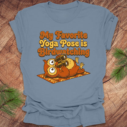 Steel blue t-shirt with owl design and text 'My Favorite Yoga Pose is Birdwatching' on a wooden surface.