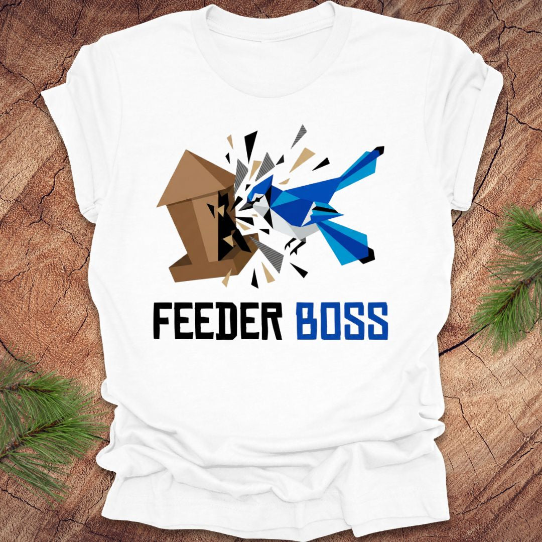 White t-shirt with a graphic design of a blue bird and birdhouse with text, 'feeder boss' on a wooden surface.