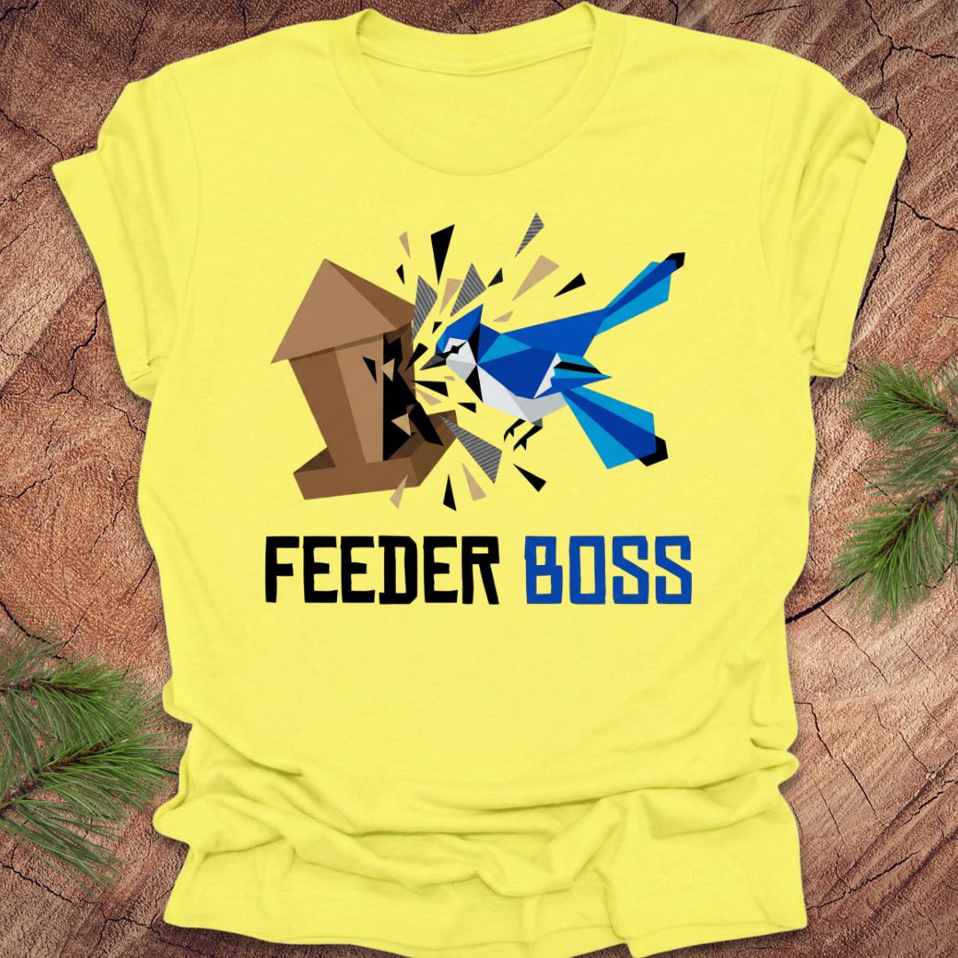 Yellow t-shirt with a graphic design of a blue bird and birdhouse, and the text 'Feeder Boss' on a wooden surface.