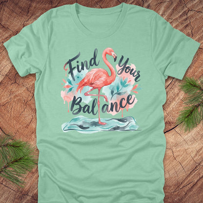 Mint green t-shirt with a flamingo graphic and text 'Find Your Balance' on a wooden surface.