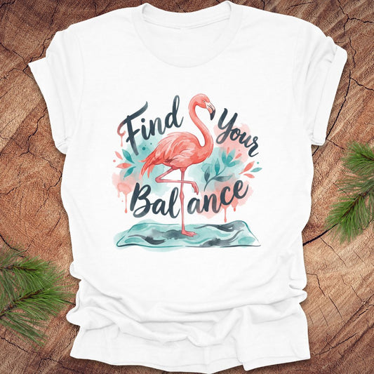 White t-shirt with a flamingo graphic and text 'Find Your Balance' on a wooden surface.