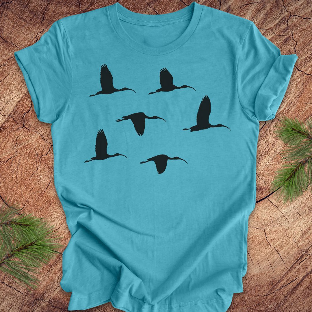 Aqua t-shirt with black ibis bird silhouettes on a wooden surface